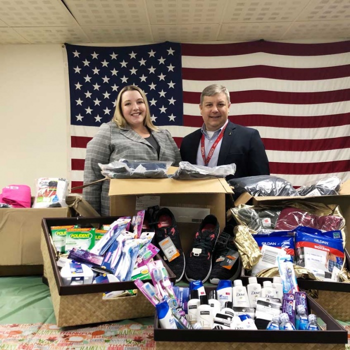 Laura Galeski, Social Responsibility Manager of Hanscom FCU and Jason Gray of the US Department of Veterans Affairs in front of a pile of donated clothing and toiletries