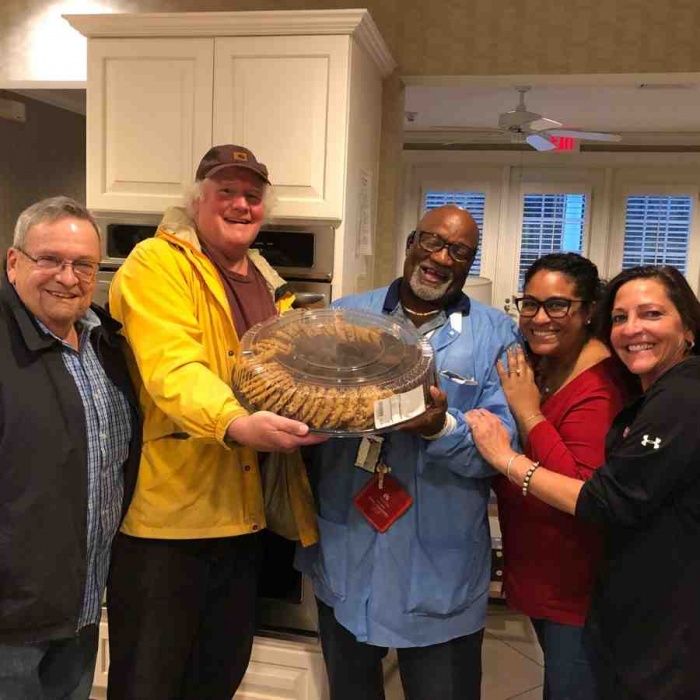 Five smiling people holding up a platter of cookies.