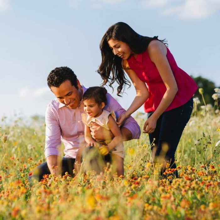 couple and child in field of yellow and orange flowers
