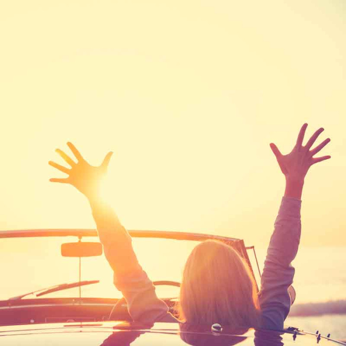 woman driving convertible car at beach sunset