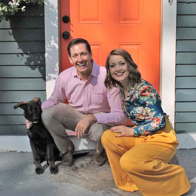 couple sitting outside front door posing with dog