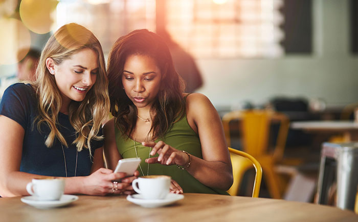 Two women having coffee and looking at a phone together