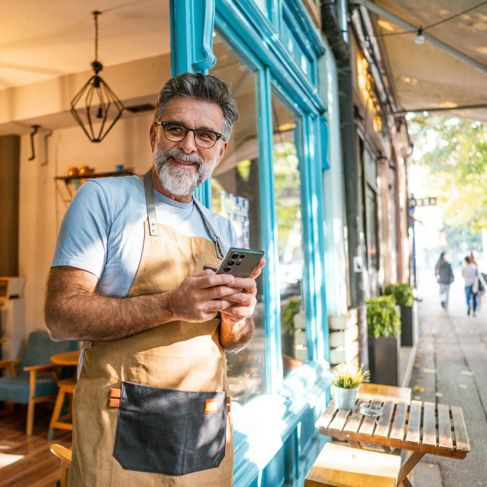 businessman in apron at door of shop